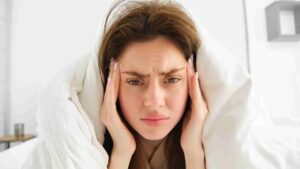 Female patient experiencing migraine symptoms with head pain and light sensitivity in a quiet room